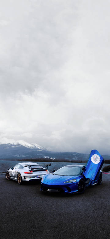 Two sports cars parked near a mountain 4K Phone Wallpaper