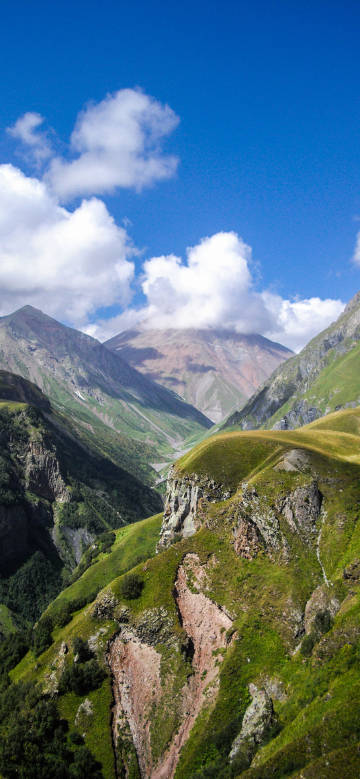 Continuous mountains, blue sky and white clouds phone wallpaper