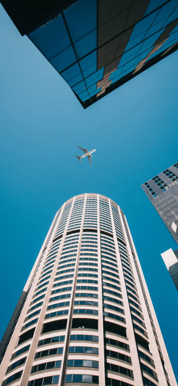 A skyscraper and an aeroplane flying through the sky