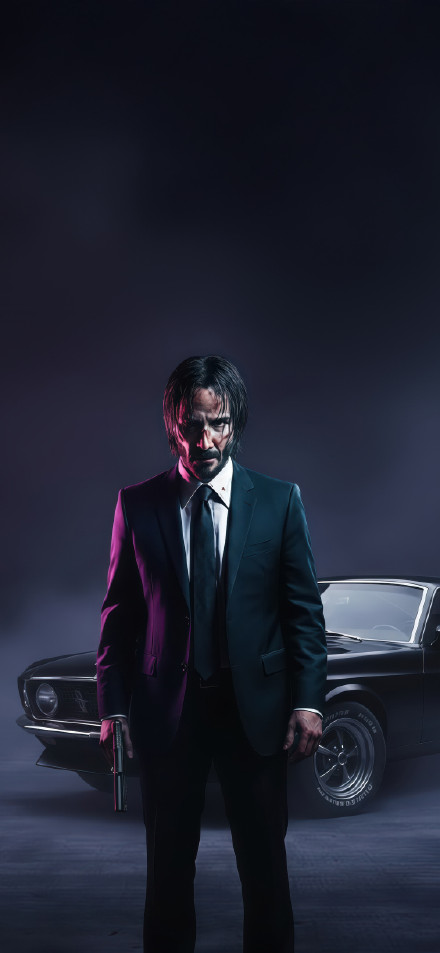 John Wick in a Suit Holding a Gun Wallpaper