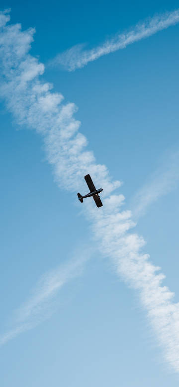Small Plane Soaring Among Sky Trails