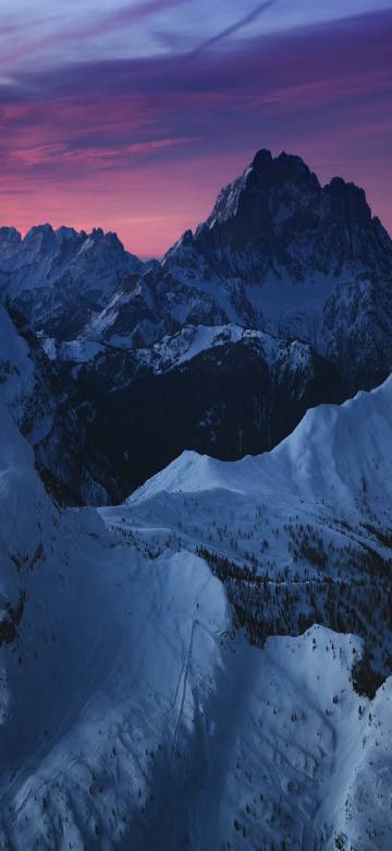Continuous snow mountains under pink and purple sky