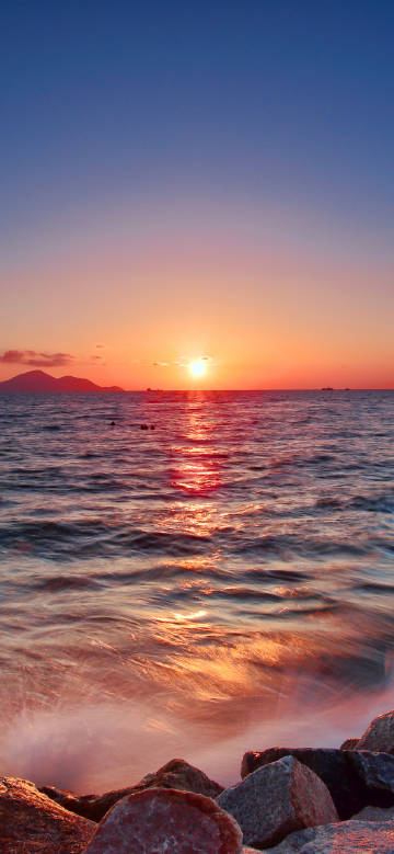 Scenery of glistening sea and rocks in the sunset glow