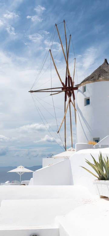White windmill in Santorini against the blue sea and sky