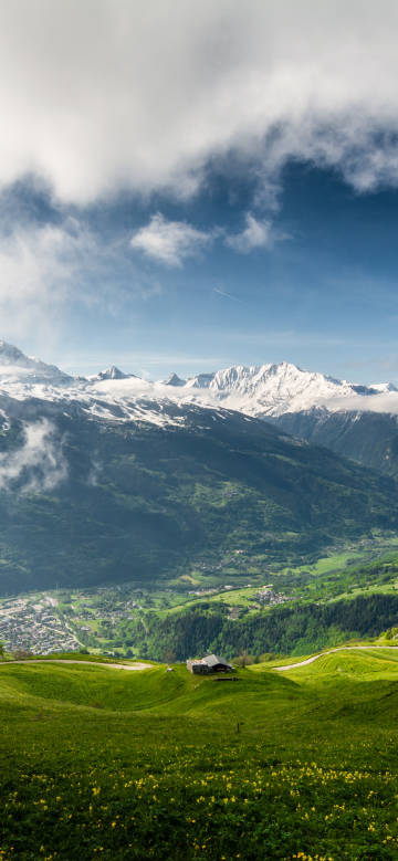 Blue sky, white clouds, snowy mountains and green fields