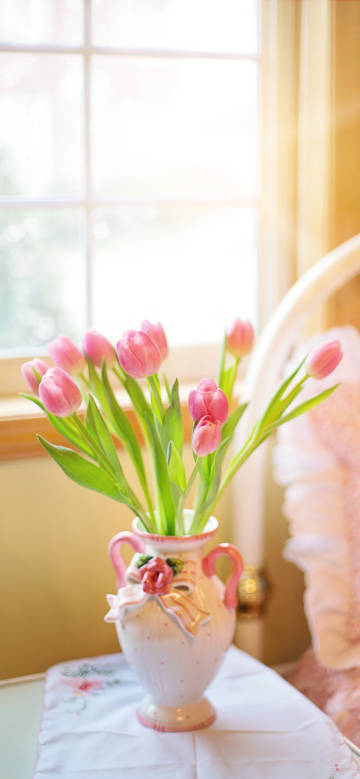 Pink tulips in a vase by the window