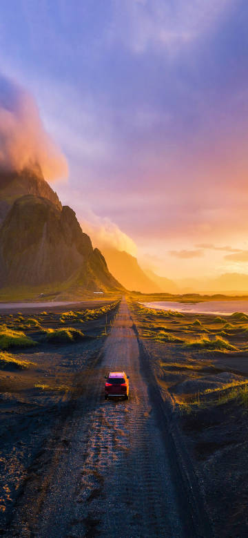 Red car driving into the distance at sunset