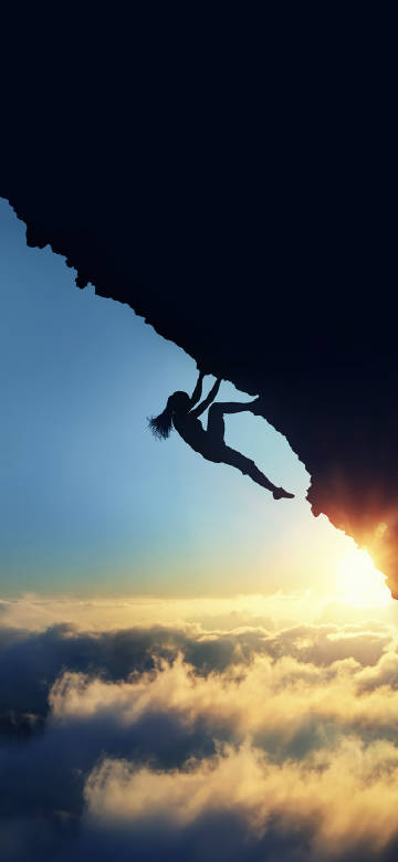 Climber on cliff above clouds
