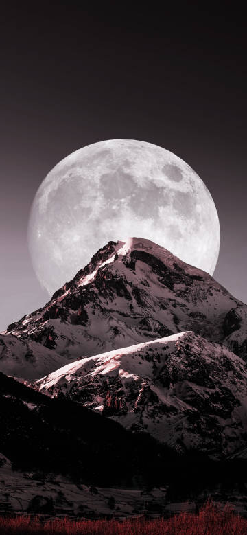 A huge bright full moon over the snowy mountains