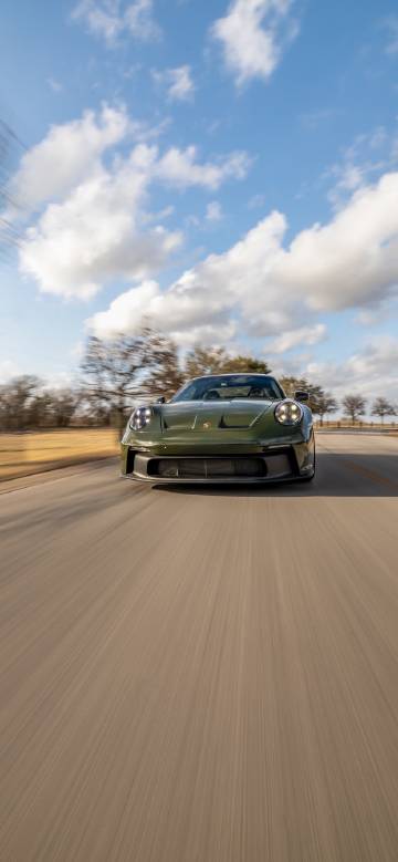 Green porsche cruising on the road