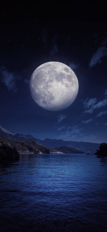 A huge bright full moon over a serene lake.