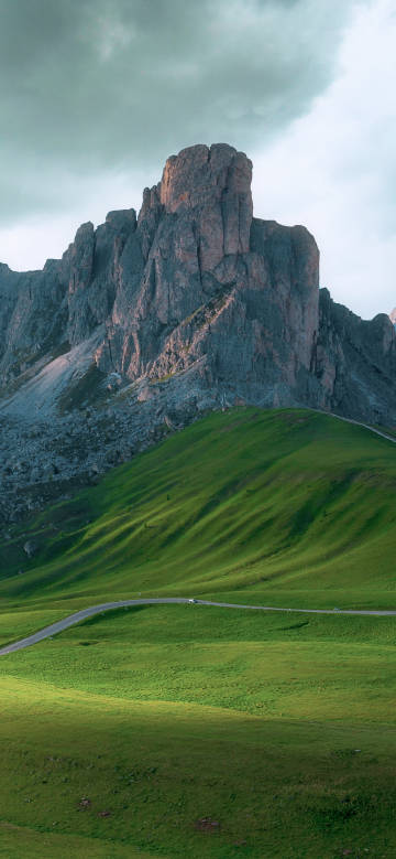 Winding road amidst green hills and steep peaks
