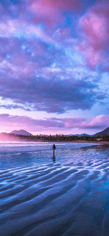 Pink and purple starry sky and a man walking on the beach