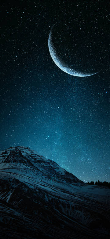 Crescent moon shining on snow-capped mountains at night