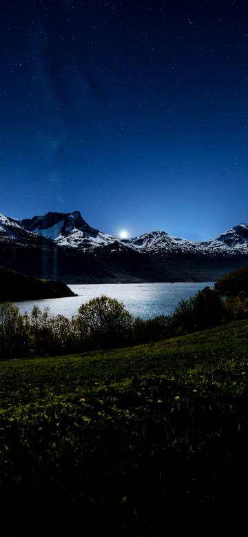 Starry night view of snow-capped mountains and lake