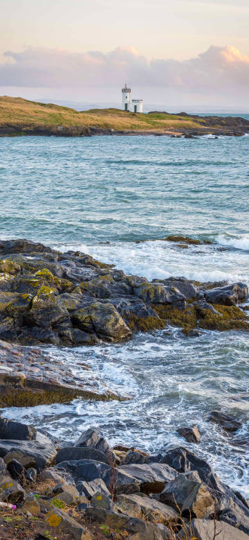 Watch the lighthouse by the waves crashing on rocks