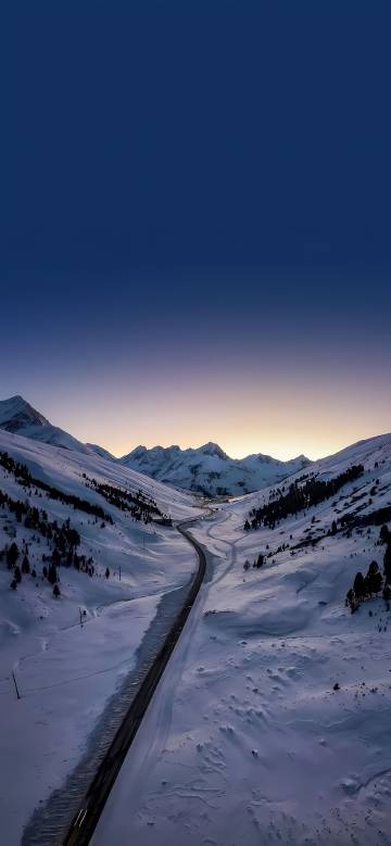 Scenic road between blue sky and snowy landscape