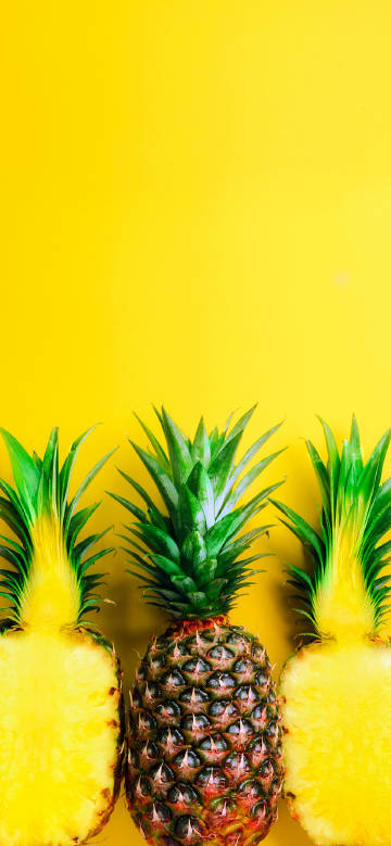 Halved pineapple on yellow background